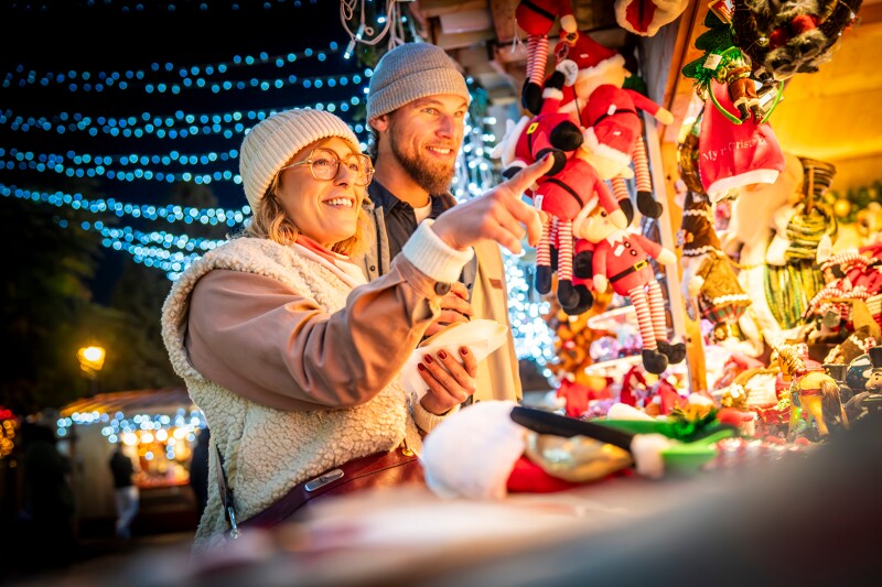 un couple au marché de noël entrain de choisir un cadeau de noël