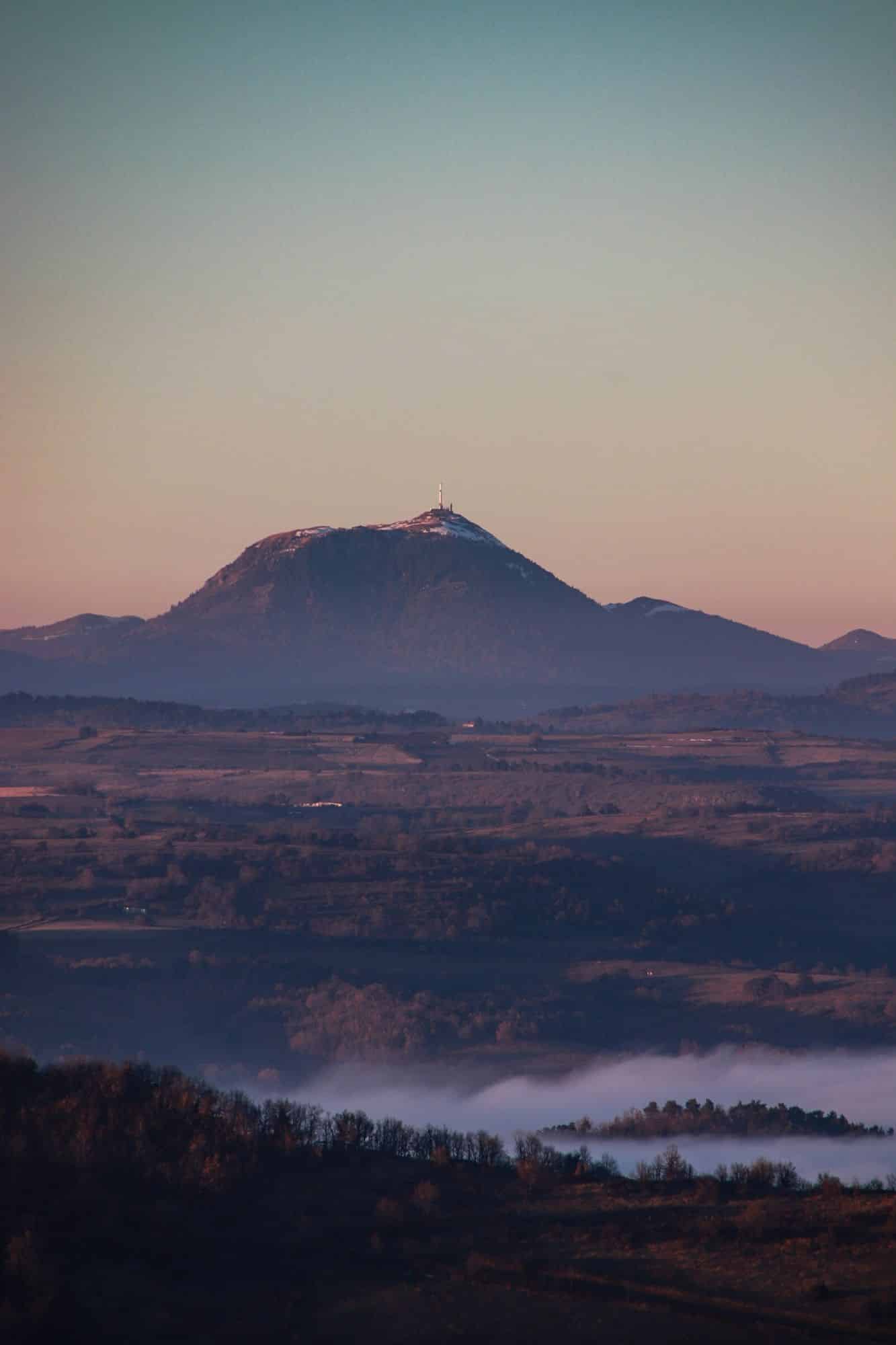 Vue sur le Puy de Dôme depuis le Pic de Brionnet avec mer de nuages. Coucher du soleil dans le Puy-de-Dôme