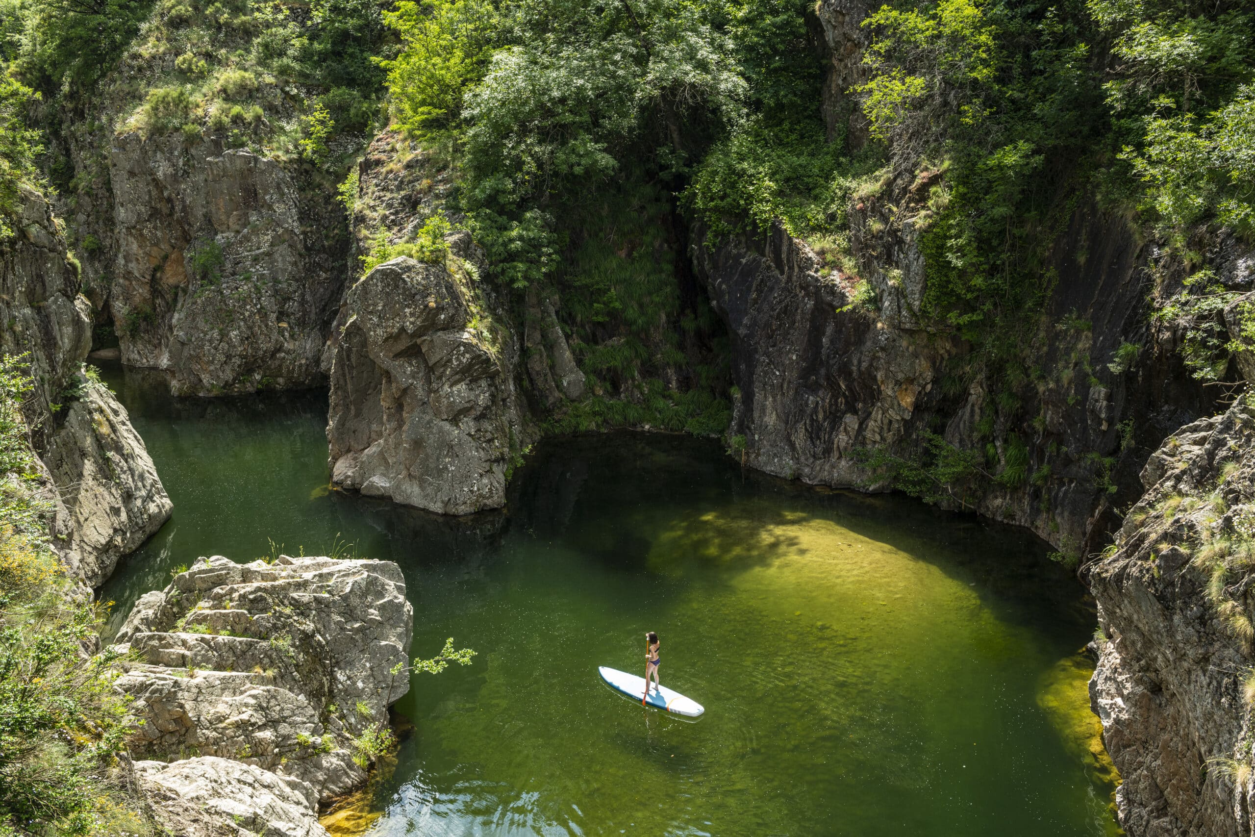 Une femme en paddle sur une rivière en Ardèche