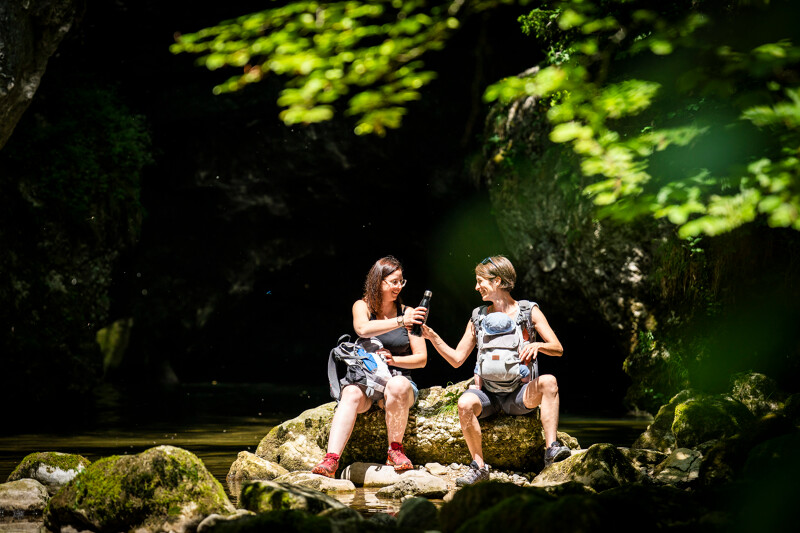 Deux femmes se partageant une gourde au bord de l'eau dans le parc naturel régional de la Chartreuse