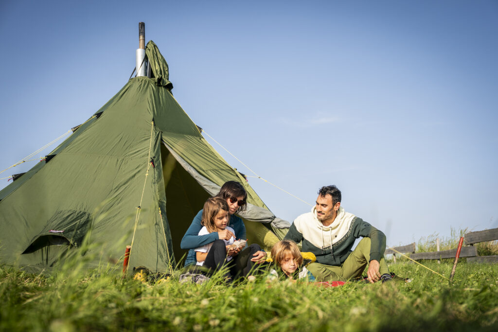 Famille de 4 personnes partageant un pique-nique devant un tipi
