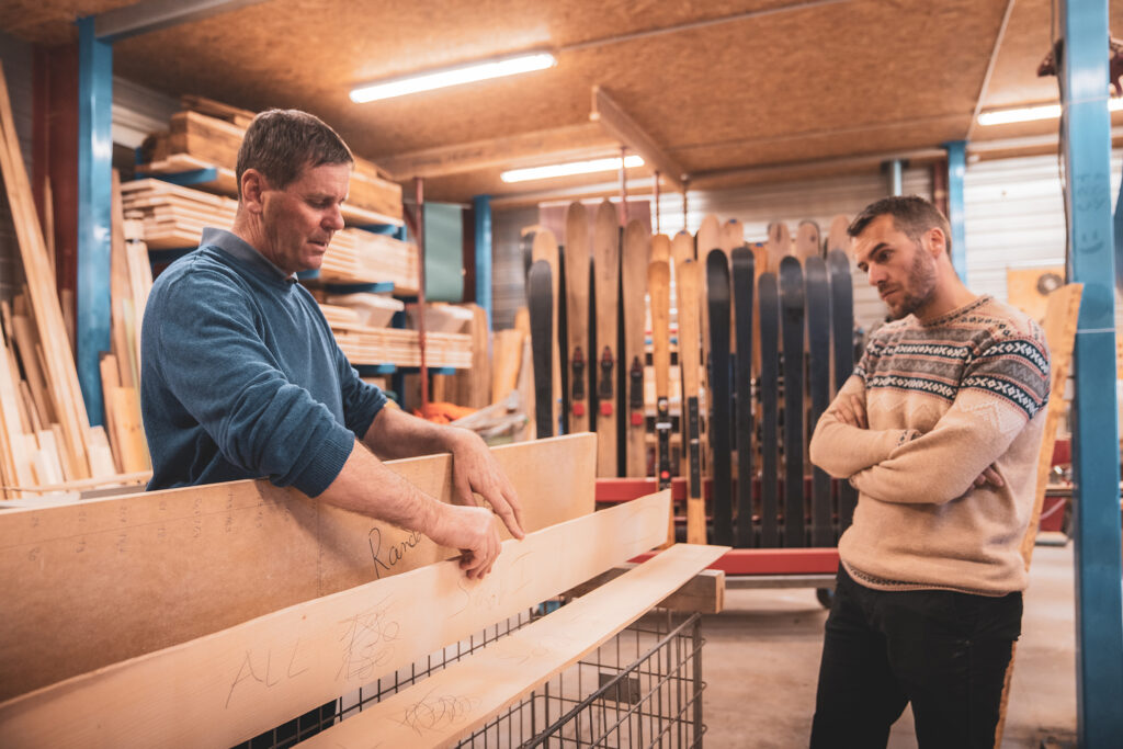 Un homme montrant la fabrication des skis en bois à un visiteur