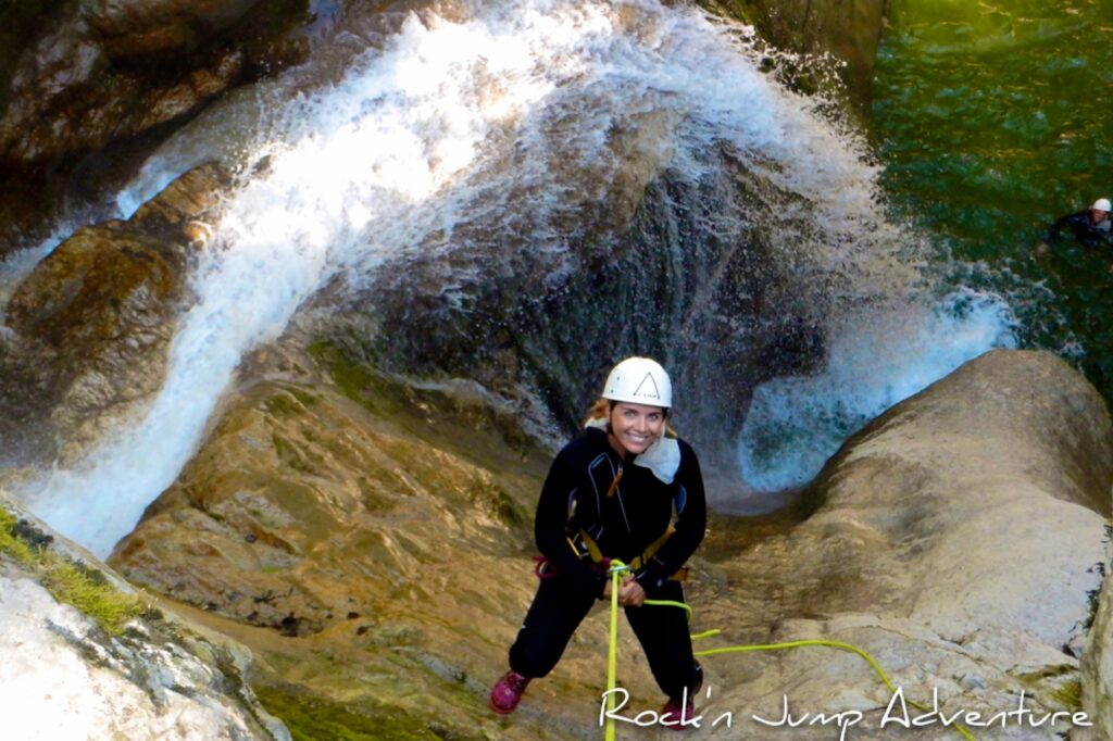 Une femme au bord d'un canyon, descendant en rappel