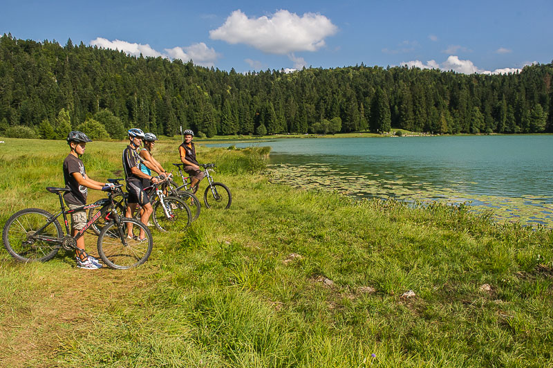 Un groupe de touristes en VTT face à un lac lors d'un séjour nature en Terre Valserhône